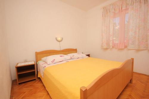 a bedroom with a yellow bed and a window at Apartments by the sea Necujam, Solta - 8691 in Nečujam