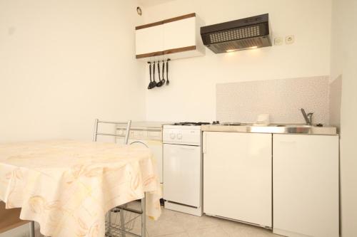 a kitchen with white appliances and a table in it at Apartment Rukavac 8863b in Rukavac