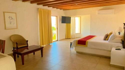 a bedroom with a bed and a table and a chair at Hotel Punta Serena & Resorts - Solo Parejas in Tenacatita