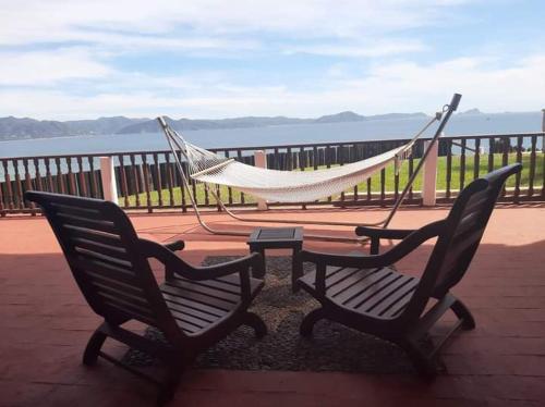 two chairs and a hammock sitting on a deck at Hotel Punta Serena & Resorts - Solo Parejas in Tenacatita