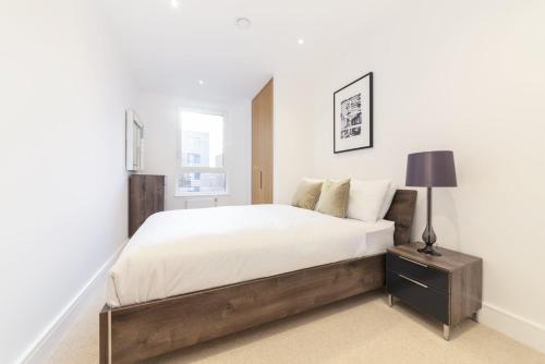 a bedroom with a large bed and a lamp on a night stand at Stylish family sized 2 bedroom apartment in London