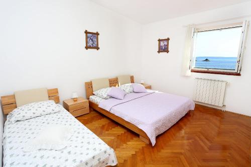 dwa łóżka w pokoju z oknem w obiekcie Seaside family friendly house with a swimming pool Seget Vranjica, Trogir - 10336 w mieście Seget Vranjica