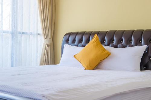 a bed with two yellow pillows and a window at Purple Flower House in Tainan