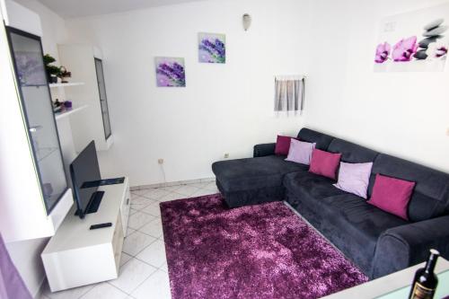 a living room with a black couch and pink pillows at Apartments by the sea Necujam, Solta - 11090 in Grohote