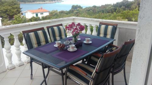 a blue table with chairs and flowers on a balcony at Apartments by the sea Necujam, Solta - 11090 in Grohote