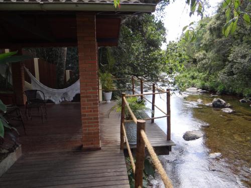 a wooden porch with a bridge over a river at Pousada da Mantiqueira in Visconde De Maua