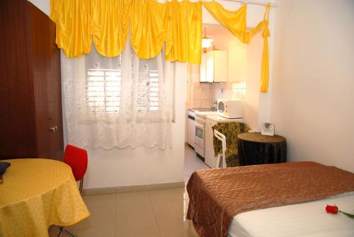 a room with two beds and a kitchen with yellow curtains at Apartments and rooms with WiFi Komiza, Vis - 11315 in Komiža