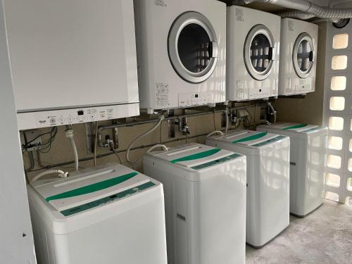 four washing machines are lined up in a laundry room at Holiday Homes TSUBOYA 202 in Naha