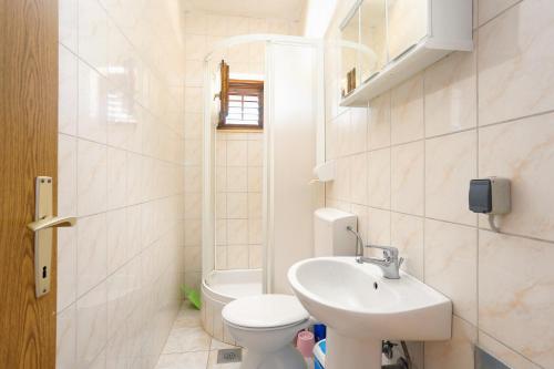 a bathroom with a white toilet and a sink at Apartments by the sea Vinisce, Trogir - 11029 in Vinišće
