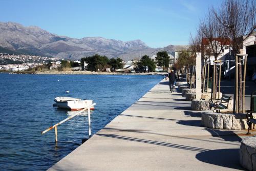 un homme se promenant le long d'un quai avec un bateau dans l'eau dans l'établissement Apartments by the sea Vranjic, Split - 11753, à Vranjic