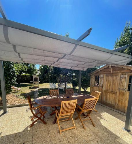une table et des chaises en bois sous un parasol blanc dans l'établissement La Baronnière de Loctudy, à Loctudy