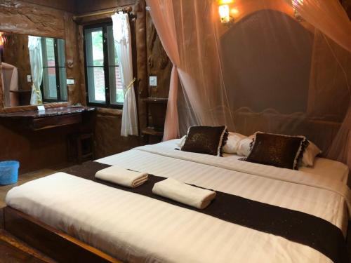 a bedroom with a large bed with two pillows at Saiyok River House in Sai Yok