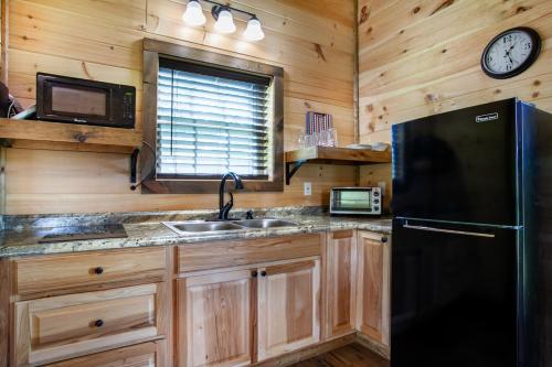 a kitchen with a black refrigerator and a sink at Patriots Tiny Home w Hot Tub Fire Pit Grill in Sevierville