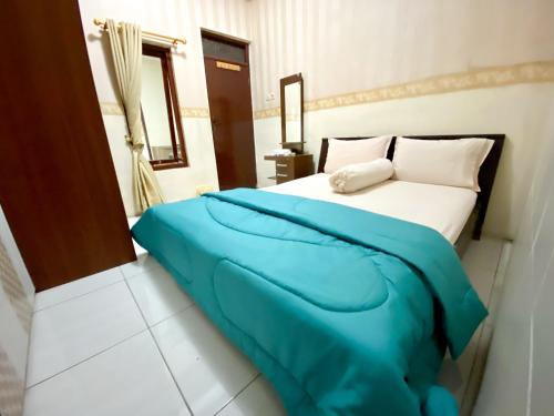a bedroom with a bed with a blue blanket at Homey Guesthouse near Sby Zoo Syariah in Surabaya