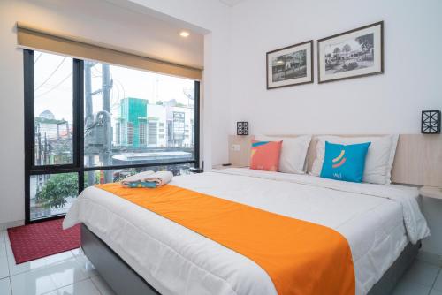 a bedroom with a large bed with a large window at Sans Hotel Fif Fa Premiere Malang by RedDoorz in Malang
