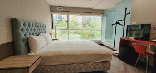 a bedroom with a bed and a tv and a window at Ximen Garden Inn in Taipei