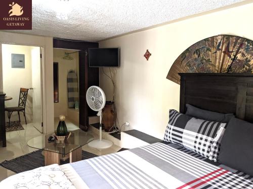 a bedroom with a bed and a table and a fan at Oasis Living Getaway in Mandeville, Manchester in Mandeville