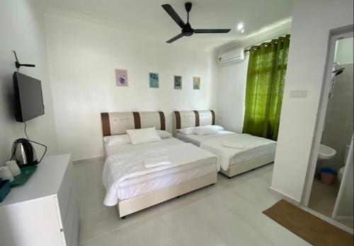 a bedroom with two beds and a television in it at dsinggahPCB Guest House in Kota Bharu