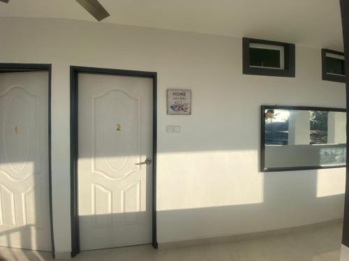 2 weiße Türen in einem Zimmer mit Spiegel in der Unterkunft dsinggahPCB Guest House in Kota Bharu