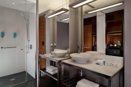 a bathroom with two sinks and a shower at Aloft London Excel in London
