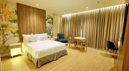 a hotel room with a bed and a table and chairs at Harolds Hotel Quezon City in Manila