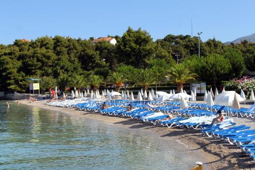 a row of lounge chairs on a beach next to the water at Apartments with a parking space Podstrana, Split - 16032 in Podstrana