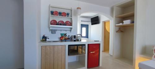 a small kitchen with a red cabinet in a room at Diana's Luxury Suites in Kithnos