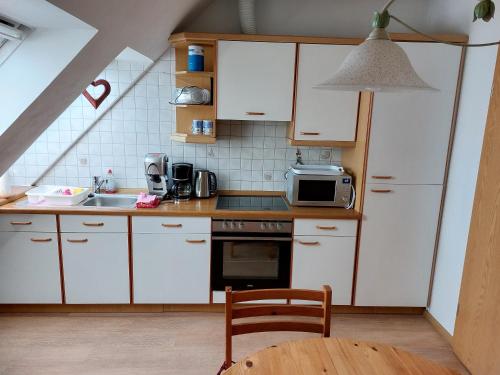 eine Küche mit weißen Schränken, einer Spüle und einer Mikrowelle in der Unterkunft Storchennest in Burg