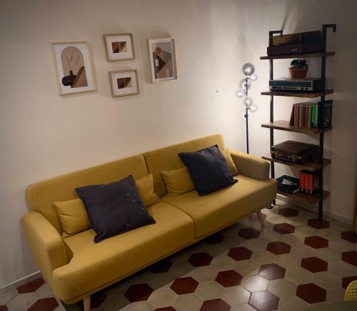 a yellow couch with two pillows in a living room at casa in oltretorrente Parma in Parma