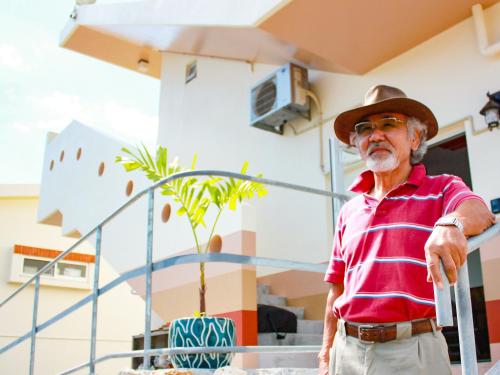 an older man wearing a hat standing next to a cake at ペンション村山里 in Yamazatu