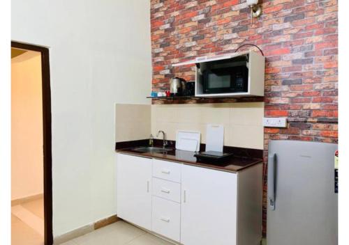 a kitchen with a counter with a microwave and a refrigerator at BluO Studio Salt Lake City - Balcony, Terrace Garden in Kolkata