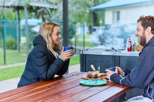 a man and woman sitting at a table drinking coffee at RAC Busselton Holiday Park in Busselton