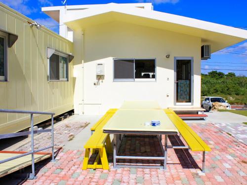 a yellow picnic table in front of a house at ペンション村山里 in Yamazatu