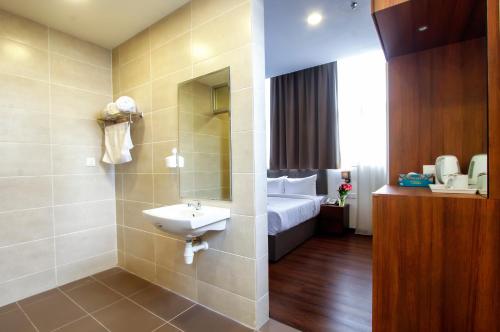 a bathroom with a sink and a bed in a room at CitiVilla Penang in George Town