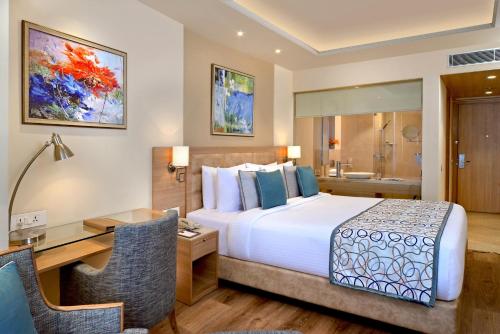 a hotel room with a bed and a desk at Golden Sarovar Portico in Amritsar