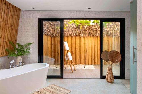Anantara World Islands Dubai Resort في دبي: حمام مع حوض أبيض وباب زجاجي منزلق