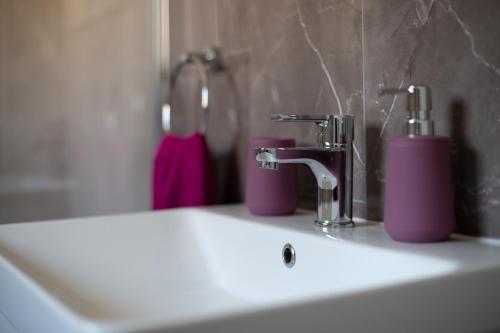 - un lavabo avec deux robinets roses dans l'établissement Apartments River, à Otočac