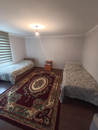 a room with two beds and a rug on the floor at "Kamchybek Ata" guest house B&B in Tërt-Kul'