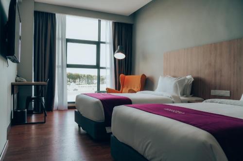 una habitación de hotel con 2 camas y una silla naranja en Amigo Hotel Bintulu en Bintulu