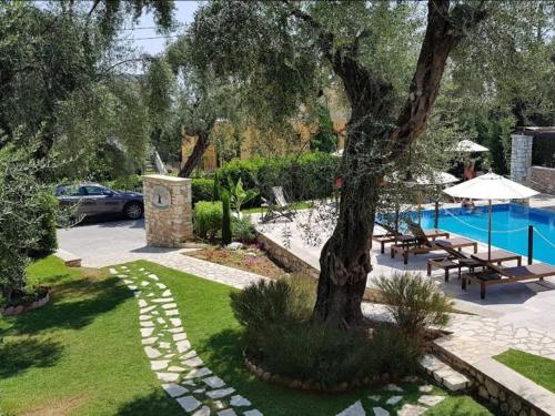 um jardim com uma árvore e uma piscina em Vassilis Guest House em Parga