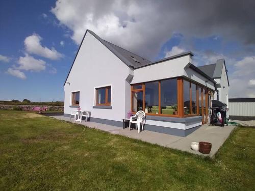a small white house with some chairs in a yard at Luxurious Property, Paddy's Haven, Wild Atlantic Way, County Clare in Kilrush
