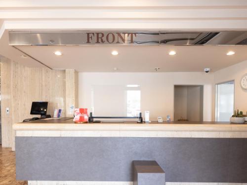 a front desk with a sign that reads front at Tabist Hotel New Osamura Sabae Inter in Fukui