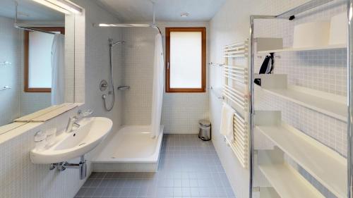 a bathroom with a sink and a shower and a tub at Reka-Feriendorf Disentis in Disentis