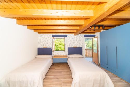a row of beds in a room with wooden ceilings at LAGA Surf VILLA by Urdaibai Rentals in Ibarrangelu