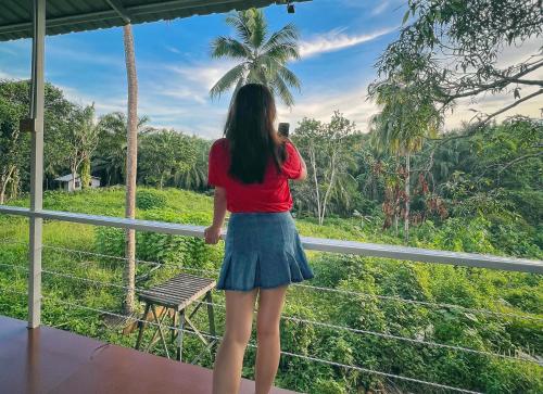 a woman taking a picture of a palm tree from a balcony at Timba Garden FREE TOWN AND JETTY TRANSPORT in Semporna