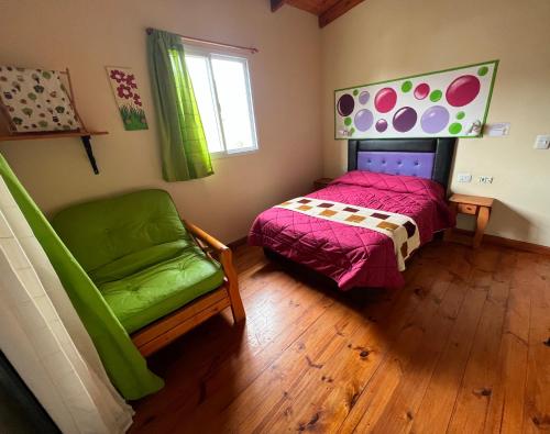 a bedroom with a bed and a chair and a window at AMANECER DE MONTAÑA in Capilla del Monte