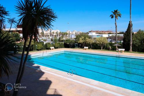 a large swimming pool with palm trees and a city at San Juan Live in Alicante