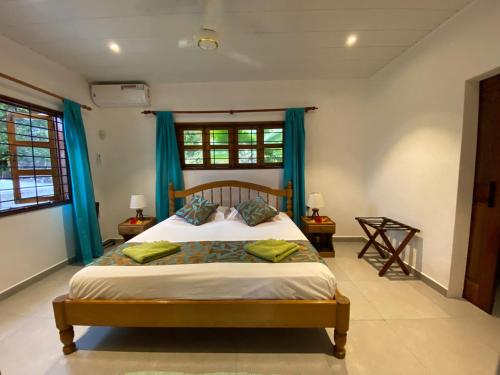 a bedroom with a large bed with blue curtains at Coin D'or in Anse Possession