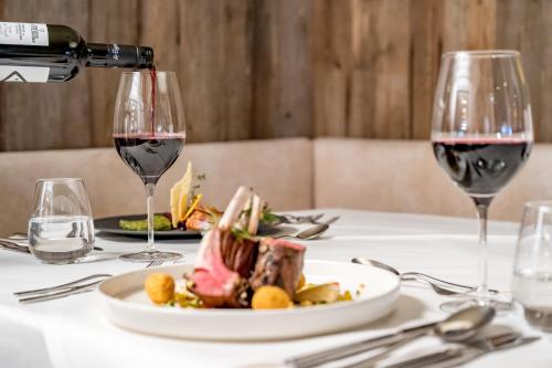 a table with a plate of food and a glass of wine at Natur & Spa Hotel Lärchenhof in Seefeld in Tirol