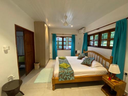 een slaapkamer met een bed met blauwe gordijnen bij Coin D'or in Anse Possession